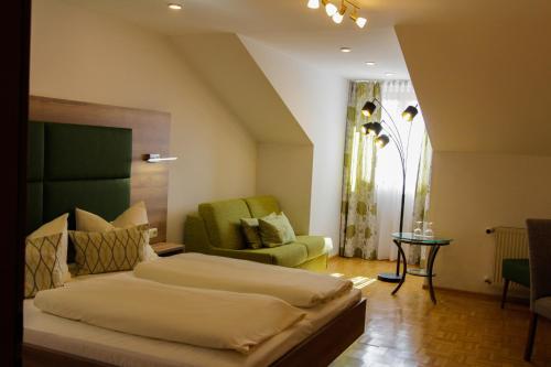 a bedroom with a bed and a green chair at Hotel Burgwirt in Deggendorf
