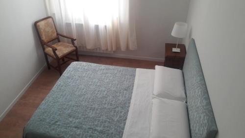 a bedroom with a bed and a chair and a window at Il Grifo Camere e Suites in Grosseto
