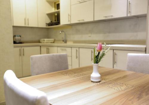 a vase with a pink flower on a table in a kitchen at Four Seasons Suites in Taif