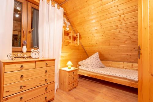 a wooden cabin with a bed and a dresser at Chaty Anety Domki Całoroczne in Solina