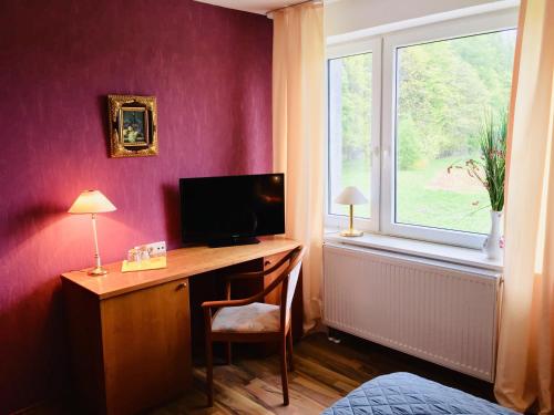 Zimmer mit einem Schreibtisch, einem TV und einem Fenster. in der Unterkunft Gästehaus hohetanne1 in Grossbreitenbach