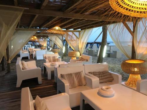 a restaurant with white couches and tables and chairs at Hotel Coucoue Lodge in Assinie