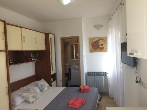- une petite chambre avec un lit et des serviettes rouges dans l'établissement Studio Apartment Mala plaža, à Kaštela
