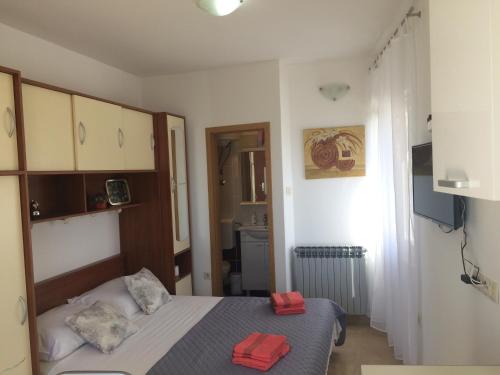 a small bedroom with a bed with red towels on it at Studio Apartment Mala plaža in Kaštela