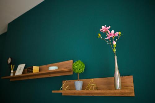 a vase with pink flowers on a wooden shelf at UNIRII OLD SQUARE APARTMENTS 4 in Timişoara