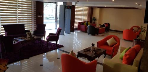 a lobby with red chairs and tables in a building at Eva Hotel Amman in Amman