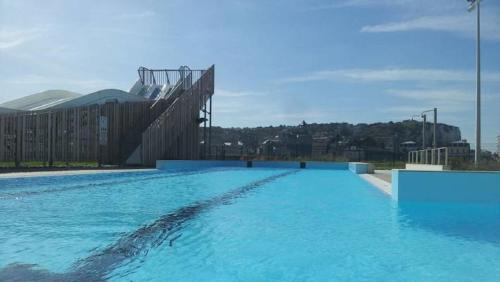 a large swimming pool with blue water in front of a building at L'ENTRE 2 COTES in Le Tréport