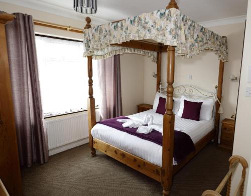 a bedroom with a four poster bed and a window at Aylesbray Lodge in Cambridge
