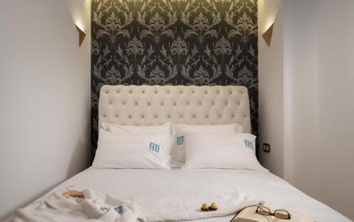 a bedroom with a bed with a black and white headboard at Pela Veranda Exquisite Suites in Neos Marmaras