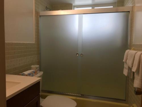 a bathroom with a glass shower door with a toilet at Shell Motel Hollywood in Hollywood