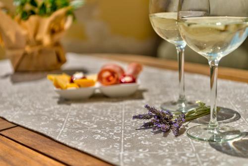 a table with two wine glasses and a bowl of fruit at Island of Luxury Apartments in Ermoupoli