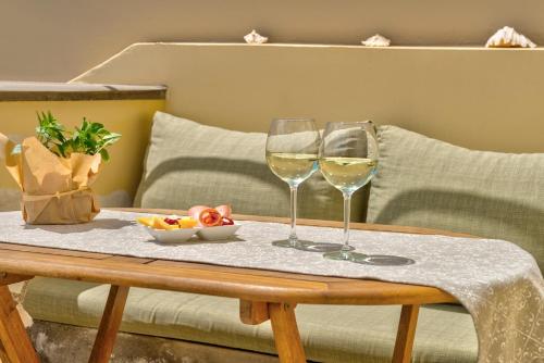 two glasses of wine and a bowl of fruit on a table at Island of Luxury Apartments in Ermoupoli