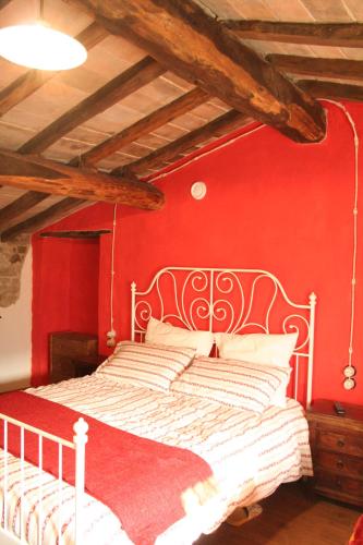 a bedroom with a white bed with a red wall at Ca' Növa in Valverde Pavia