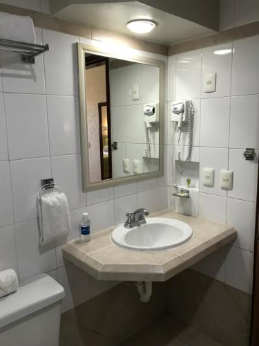 a bathroom with a sink and a mirror and a toilet at Olas Altas Inn Hotel & Spa in Mazatlán