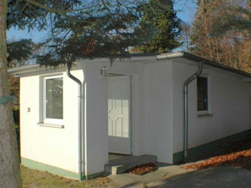 een kleine witte schuur met een deur en een boom bij Ferienhaus Sonnensteg in Ostseebad Sellin