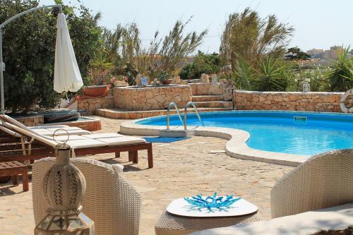 a swimming pool with chairs and a table and an umbrella at Hotel Luagos club in Lampedusa