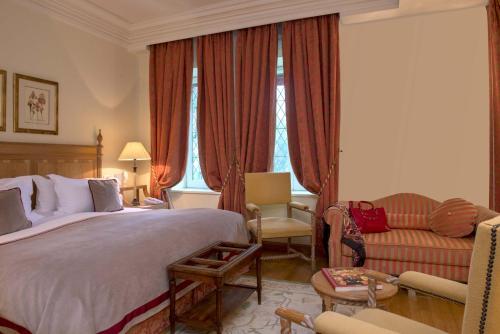a hotel room with a bed and a chair and a couch at Hotel de la Cité Carcassonne - MGallery Collection in Carcassonne