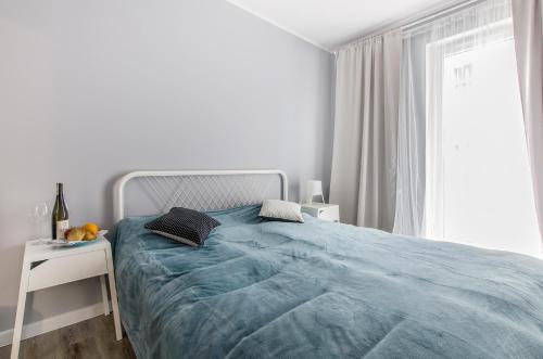 a white bedroom with a blue bed and a window at Smart Rental Management Apartments in Wrocław