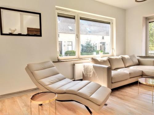 una sala de estar con muebles y ventanas blancos. en Friesenbude Deluxe, en Jever