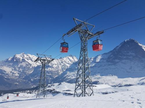 two ski lifts in the snow with a mountain at Angie's Apartments in Lauterbrunnen