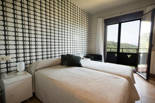 a bedroom with a bed and a large window at Hotel Restaurante Novella in Benasal