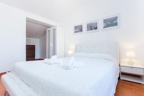 a white bedroom with a white bed and two lamps at Safari Beach guest house in Lagos