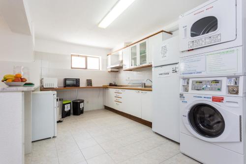 a kitchen with white cabinets and a washer and dryer at Safari Beach guest house in Lagos