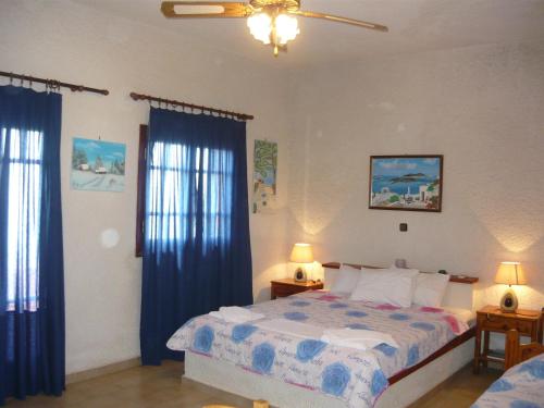 マクリ・ギアロスにあるVilla Victoriaのベッドルーム1室(ベッド1台付)、青いカーテン付きの窓2つが備わります。