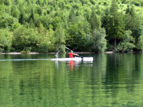 a person is rowing a boat on a lake at Zajček Apartma in Mojstrana