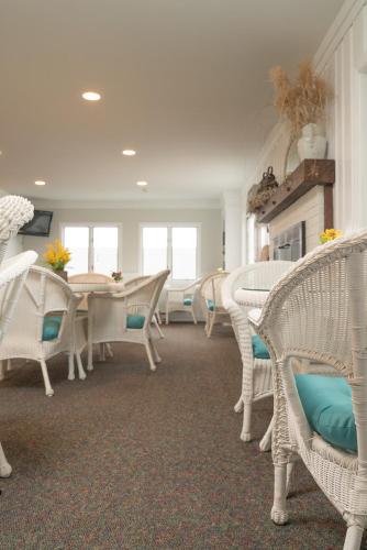 a dining room with white wicker chairs and a table at Auberge on the Cove in Ogunquit