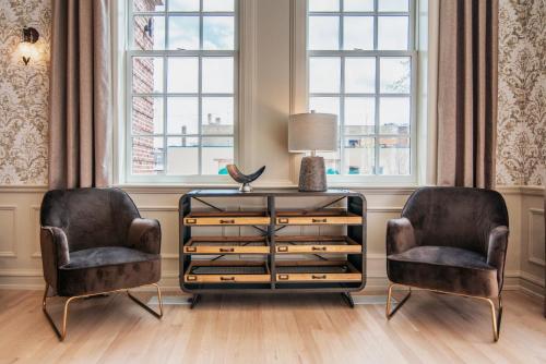 two chairs and a dresser in a room with windows at The Stella Hotel & Ballroom in Kenosha
