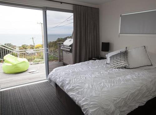 ein Schlafzimmer mit einem Bett und einem Balkon in der Unterkunft Bayview Retreat in Oneroa