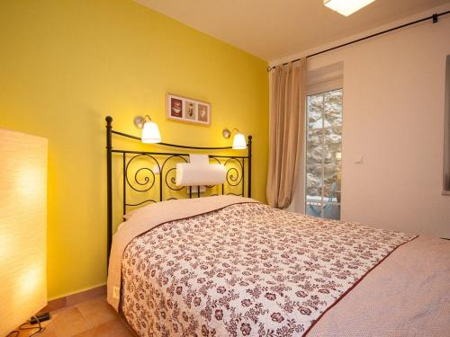ein Schlafzimmer mit einem Bett mit gelben Wänden und einem Fenster in der Unterkunft Apartments Mediteranea in Baška