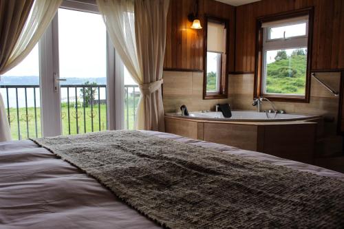 um quarto com uma cama, uma banheira e uma janela em Hotel Aliwen em Dalcahue