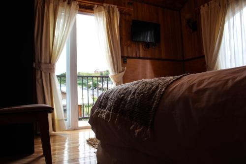 1 dormitorio con 1 cama y puerta corredera de cristal en Hotel Aliwen, en Dalcahue