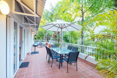 a patio with a table and chairs and an umbrella at Balboa Apartments in Port Douglas