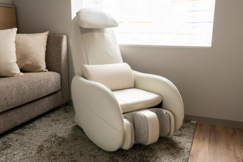 a white chair in a living room next to a couch at remm Tokyo Kyobashi in Tokyo