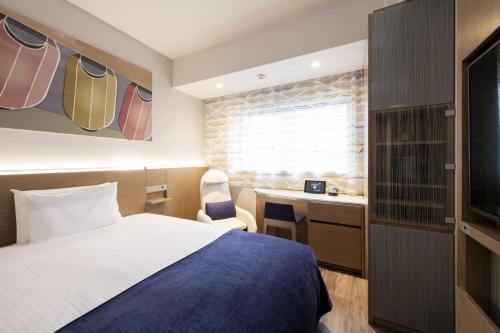 a hotel room with a bed and a desk at remm Tokyo Kyobashi in Tokyo