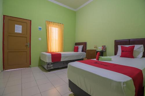 una habitación de hotel con 2 camas y una puerta en RedDoorz near Kampus UMP Purwokerto, en Purwokerto