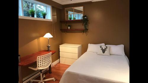 a bedroom with a bed and a desk and windows at Le 154 Jacques-Cartier in Gaspé