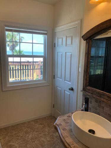 a bathroom with a large white sink and a window at Capri Beach Hotel in Corpus Christi