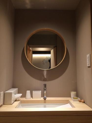 La salle de bains est pourvue d'un lavabo et d'un miroir rond. dans l'établissement WOW-GINZA, à Tokyo