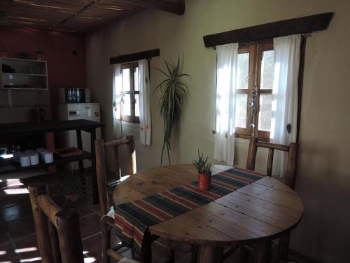 Habitación con mesa de madera, sillas y ventanas. en Karallantay en Tilcara