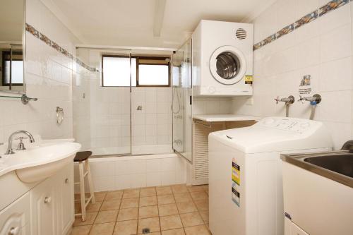 a white bathroom with a sink and a washing machine at Lowanna Unit 10 24 Bulcock Beach Esplanade Bulcock Beach in Caloundra