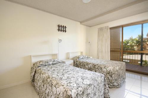 two beds in a room with a balcony at Lowanna Unit 10 24 Bulcock Beach Esplanade Bulcock Beach in Caloundra