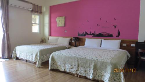 two beds in a room with a pink wall at 2013 Homestay in Taitung City