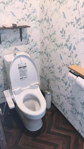 a white toilet in a bathroom with floral wallpaper at Guest house & Bar Diamond Head in Mihana