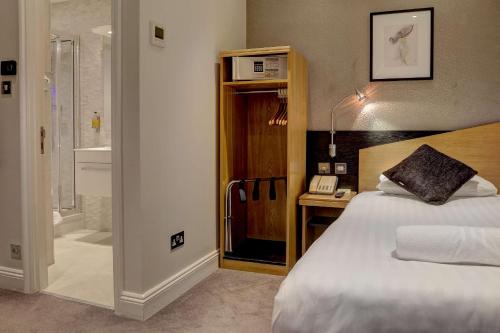 a hotel room with a bed and a phone and a bathroom at Best Western Buckingham Palace Rd in London