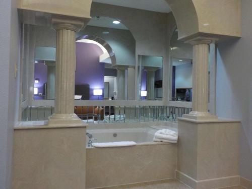 a bathroom with a tub with a large mirror at SureStay Plus Hotel by Best Western Warner Robins AFB in Warner Robins