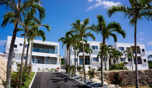a white building with palm trees in front of it at Crystal Villa Imgya in Miyako Island